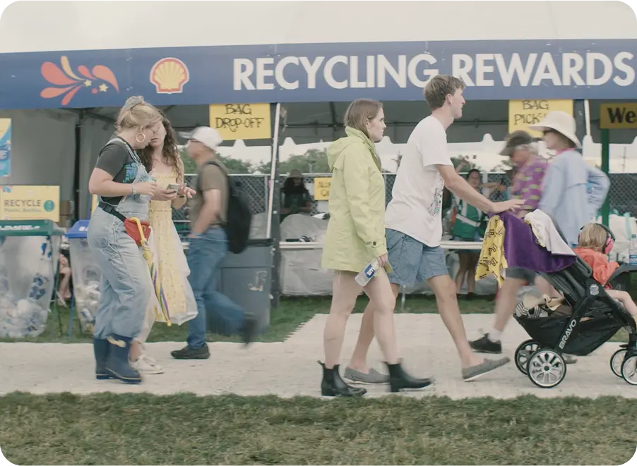Festival attendees walk past recycling area of festival 