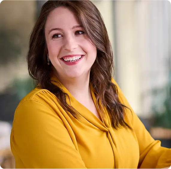 Shell employee heather sitting at her desk in a yellow blouse smiling