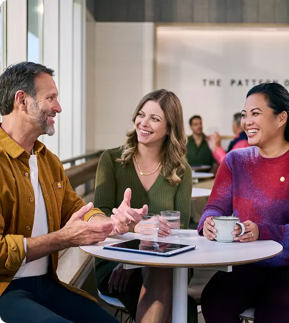 Man and two women laughing at a table together